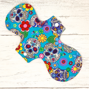 Reusable cloth sanitary pad with bright blue sugar skulls pattern
