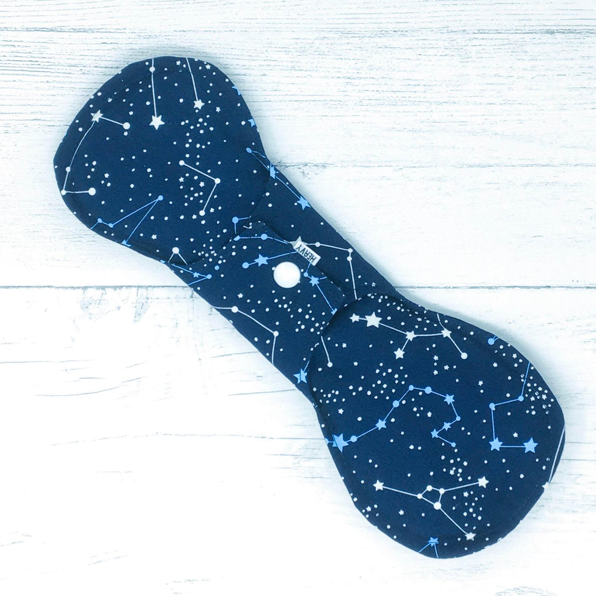 11" Reusable menstrual pad with pattern of constellations on a navy cotton fabric. Reverse of fastened pad