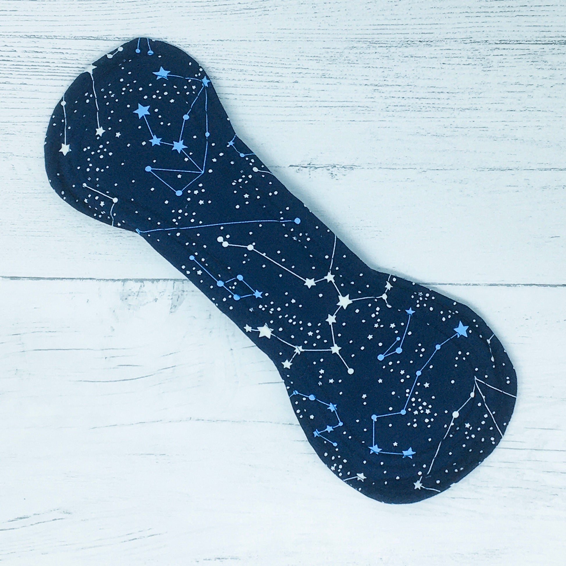 11" Reusable menstrual pad with pattern of constellations on a navy cotton fabric. Front view of fastened pad